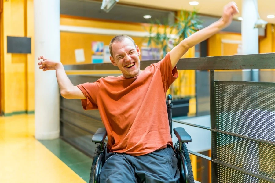 Happy disabled man in wheelchair with arms in the air